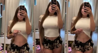 Amanda, toda poderosa com sua blusinha branca e um shortinho, se admirando no espelho