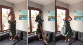 Irina de roupão no sofá, tirando a roupa